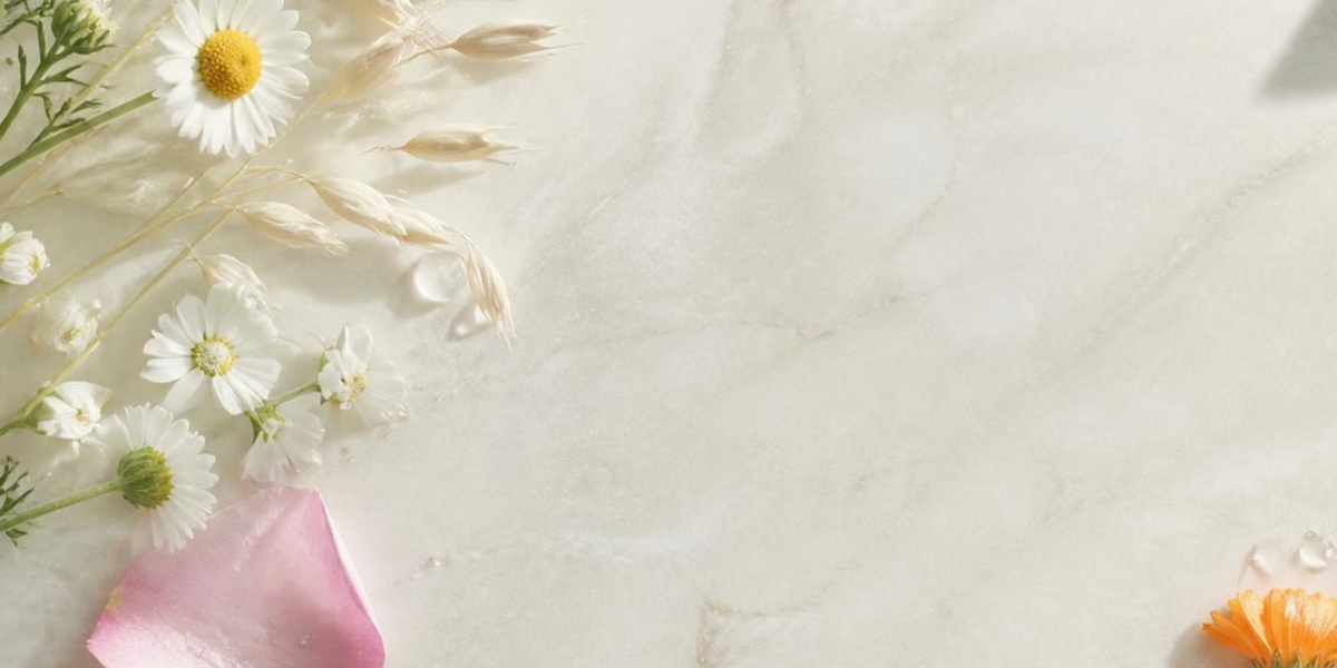 image of cream background with a petal, some flowers and a couple of drops of oil.