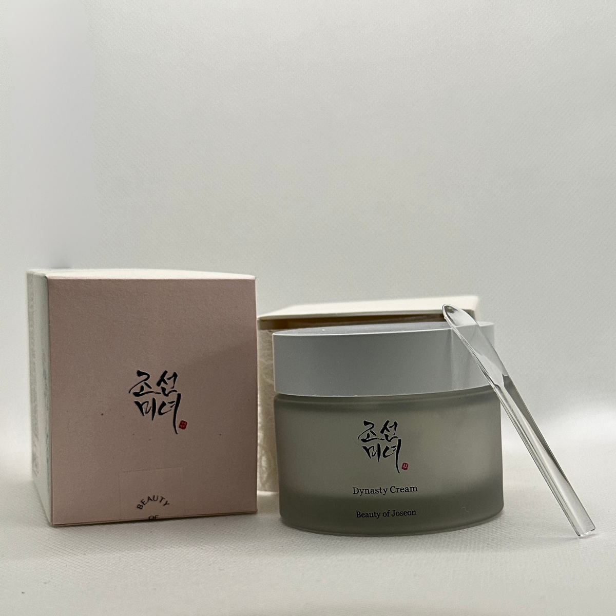 Beauty of Joseon Dynasty Cream 50ml sits next to its box with it's clear plastic spatular to enable the user to hygienically scoop out the cream.