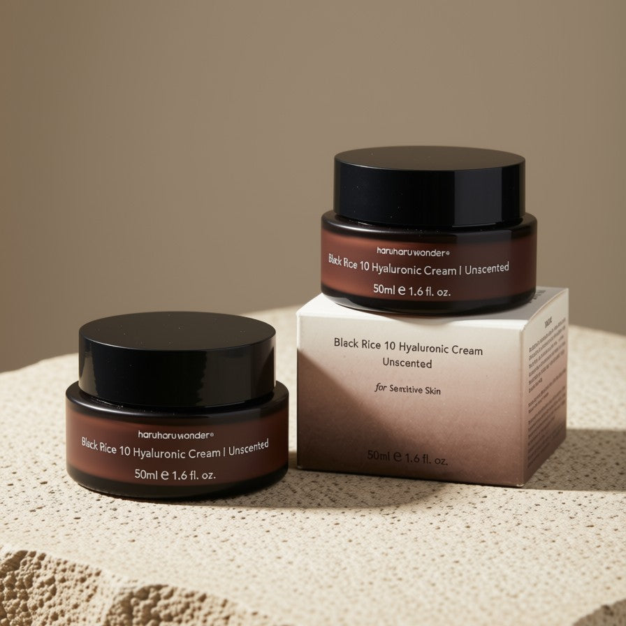 Two jars of Haruharu Wonder Black Rice 10 Hyaluronic Cream 50ml alongside its product box, styled on a textured beige stone surface against a solid warm beige background.