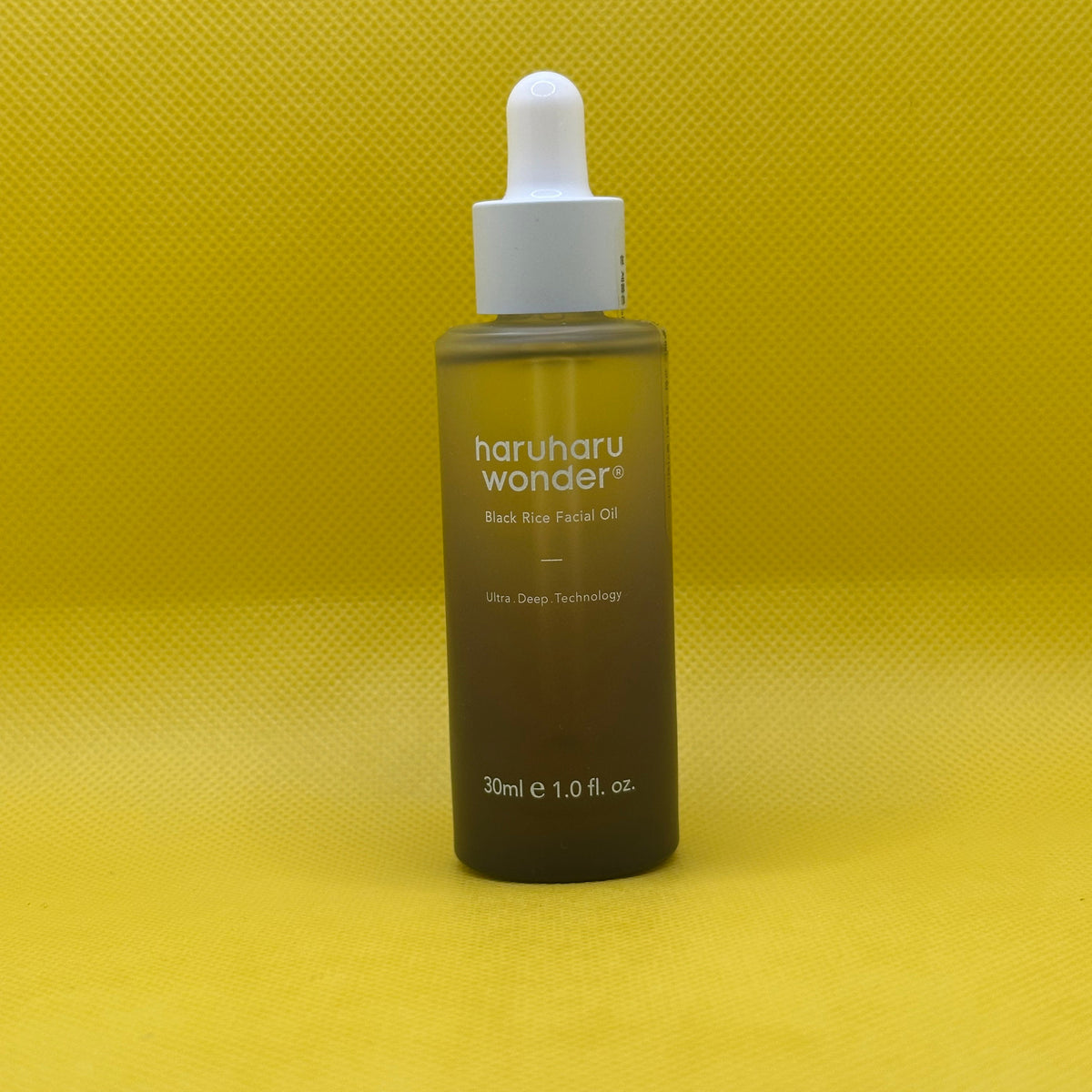 A 30ml bottle of haruharu wonder Back Rice Facial Oil with a white dropper cap, set against a bright yellow textured background.