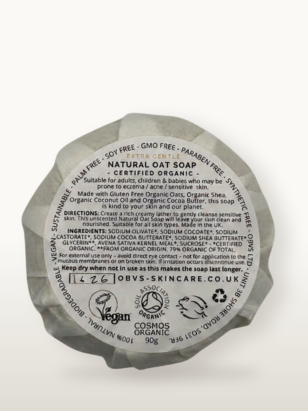 The back of a round soap. The label reads: 100% natural - Biodegradable - Vegan - Sustainable - Palm free - Soy free- GMO free - Paraben free - Synthetic free - Obvs Ltd - Unit 3B Shore Road, S031 9FR,. Extra gentle. Natural Oat Soap. Certified Organic. Suitable for adults, children and babies who may be prone to eczema / acne / sensitive skin. Made with gluten free organic oats, organic shea, organic cocoa butter, this soap is kind to your skin and our planet. Cosmos Organic.