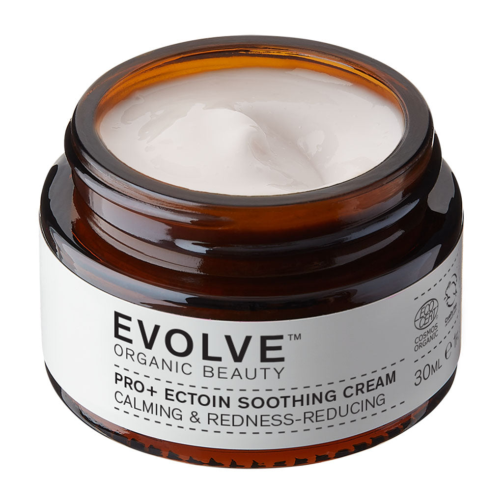 An open amber glass jar of Evolve Organic Beauty Pro+ Ectoin Soothing Cream, showing the white cream inside, on a solid white background.
