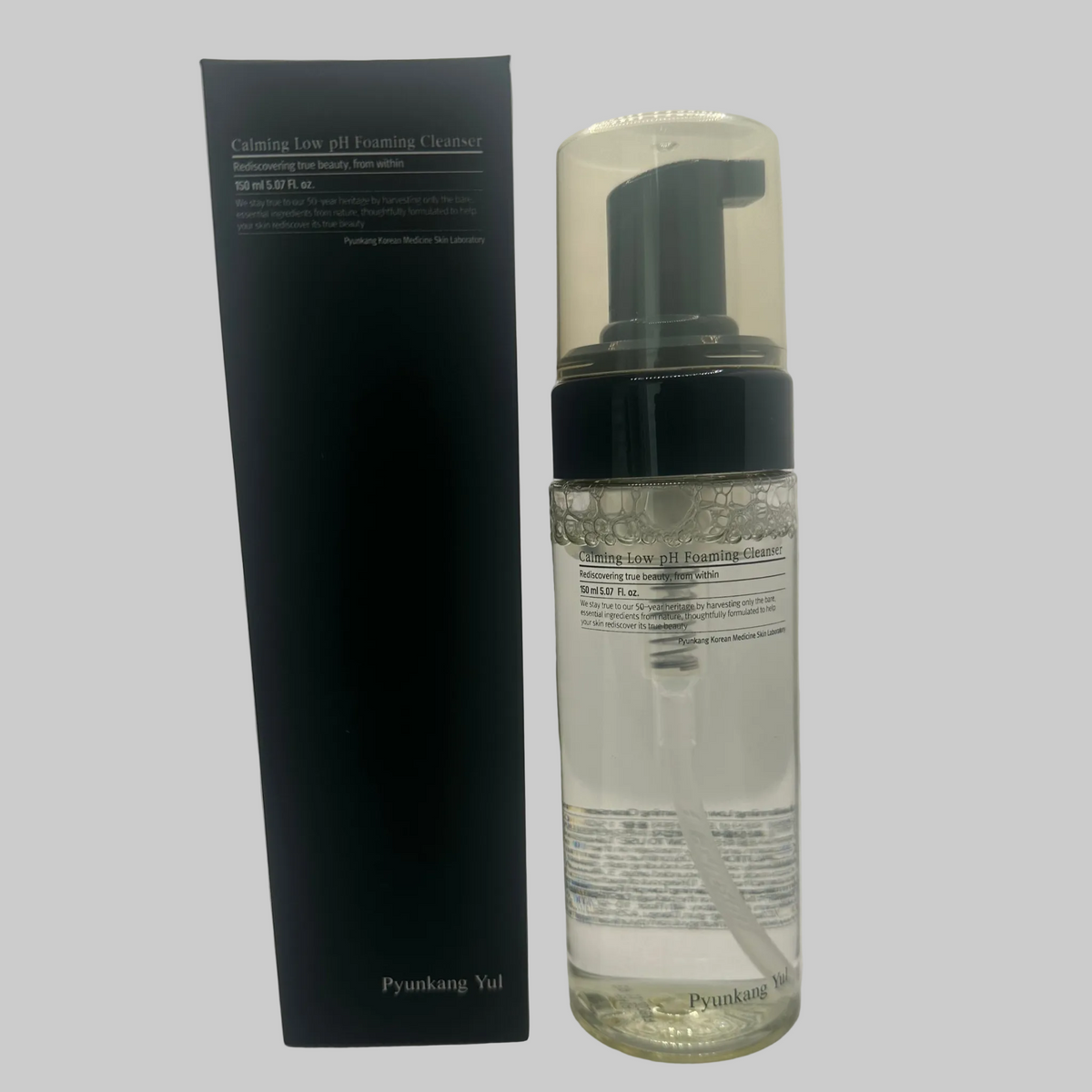 A clear bottle of Pyunkang Yul Low pH Foaing Cleanser 150ml stands next to its black box. Box reads: Redescovering true beauty, from within.