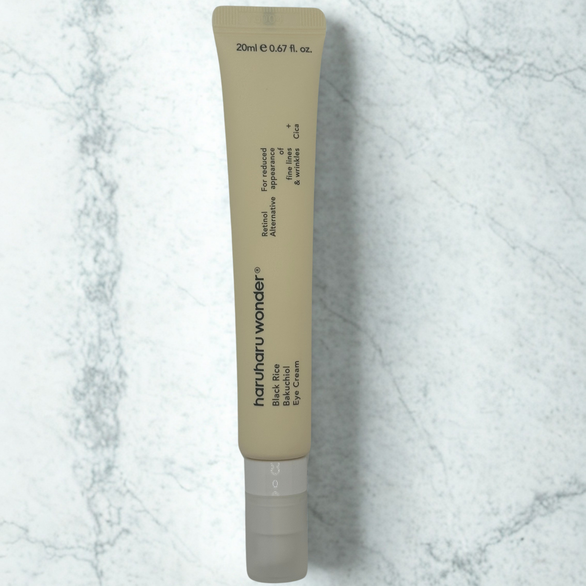 A 20ml squeeze tube of haruharu wonder Black Rice Bakuchiol Eye Cream, featuring a beige body and a frosted cap, set against a light gray and white marble background. The tube reads: Retinol Alternative For Reduced Appearance of fine lines & wrinkles.