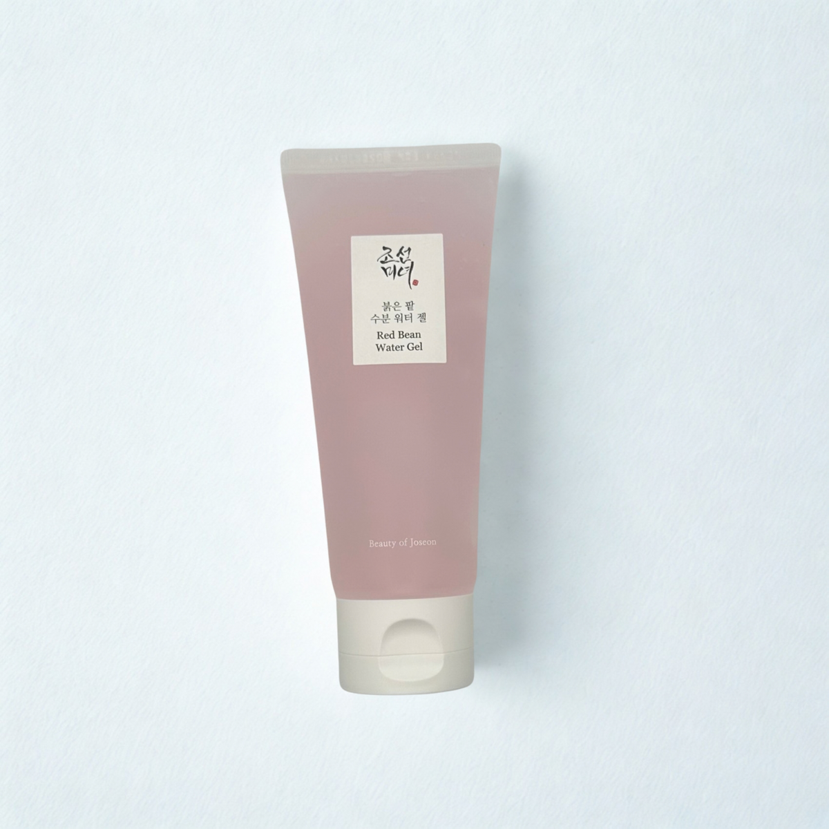 A tube of Beauty of Joseon Red Bean Water Gel with a soft pink body and a white cap, shown against a white textured background.