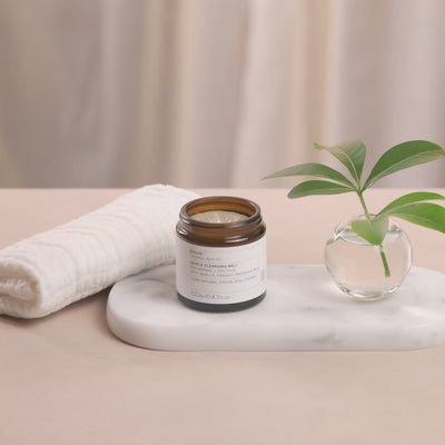 Video of a woman massaging the Evolve Gentle Cleansing Melt into her own face and then wiped off with a white flannel.
